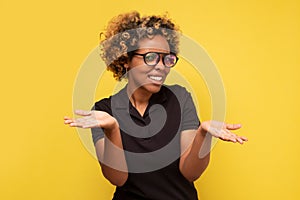 Young african woman with arms out, shrugging her shoulders, saying who cares, so what now