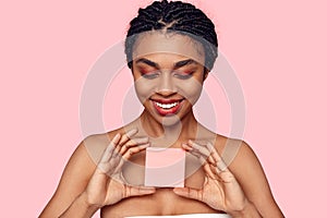 Beauty Concept. Young african woman wearing makeup isolated on pink with sticker copy space smiling happy