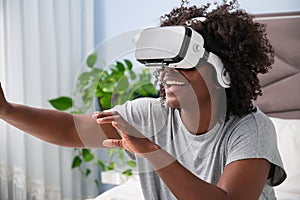 Young african woman experiencing virtual reality on her bed.