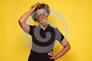 Young african woman in glasses scratching head, thinking daydreaming deeply about something