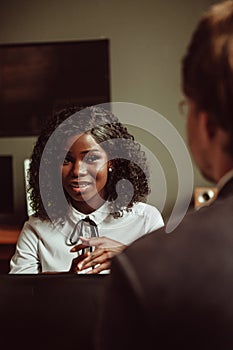 Young African woman in an interview or at business meeting. Selective focus on smiling female face. Portrait of dark