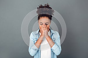 Young african woman isolated on grey wall studio casual daily lifestyle sneezing