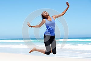 Young african woman jumping with joy at the beach