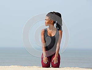 Young african woman kneeling outdoors on beach