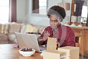 Young African woman labeling packages while working from home