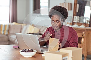 Young African woman labeling packages while working from home photo