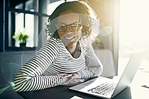 Young African woman laughing while working on a laptop