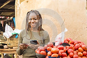 young african woman in a local african market using her mobile phone and credit card
