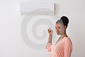 Woman Operating Air Conditioner With Remote Control