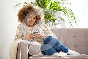 Young african woman relaxing at home and using mobile phone