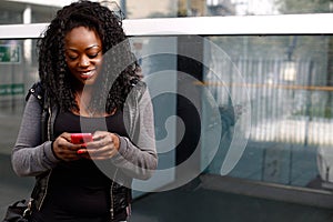 Young African woman sending an sms on her mobile