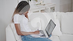 Young african woman sit on couch at home talk by webcam video conference call chatting with distance teacher