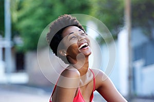 Young african woman sitting outdoors and laughing