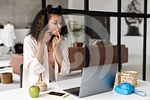 Young african woman squeezing zit while watching photo