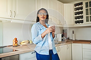 Young African woman standing in her kitchen drinking coffee
