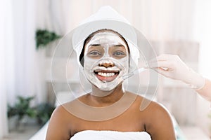 Young African woman in Studio doing body care with refreshing facial mask for young and beautiful skin and relaxation