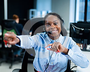 Young african woman talking to a client on a headset. Happy female call center employee.