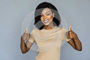 Young african woman with thumbs up isolated on grey wall casual daily lifestyle