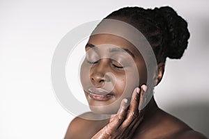 Young African woman touching her cheek against a white background