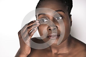 Young African woman touching the skin around her eyes