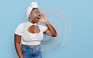 Young african woman with turban wearing hair turban over isolated background shouting and screaming loud to side with hand on
