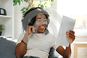 Young african woman using digital tablet and smiling while resting at home.