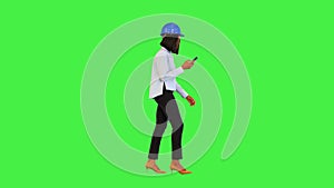 Young african woman walk, read or type message on smartphone wearing protective construction helmet on a Green Screen