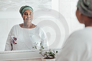 Young African woman wearing a headscarf looking in the mirror