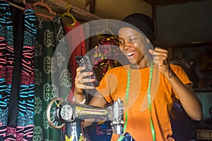 African woman who is a tailor feeling excited and happy and jubilant while viewing content on her mobile phone photo