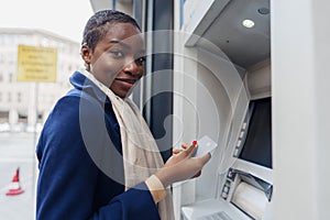 Young african woman withdrawing cash at the ATM close up