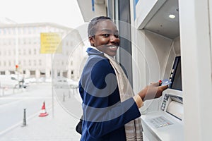 Young african woman withdrawing cash at the ATM close up
