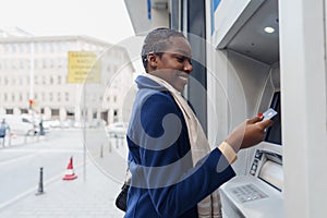 Young african woman withdrawing cash at the ATM close up