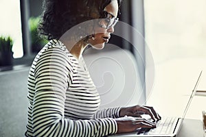 Young African woman working on a laptop at a table