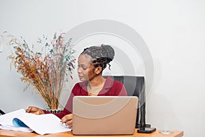 Young African woman is working at a table in a modern office setting.