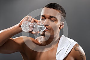 Young Africana sportsman drinking water after