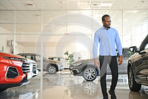 young africanamerican man came to see automobiles in dealership or cars showroom