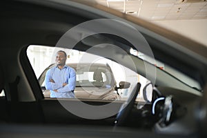 young africanamerican man came to see automobiles in dealership or cars showroom