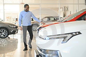 young africanamerican man came to see automobiles in dealership or cars showroom