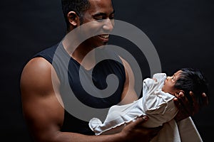 Young afro-american daddy holding his sweet newborn baby in the arms