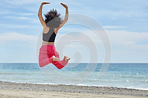 Young afro american dancer jumping on beach