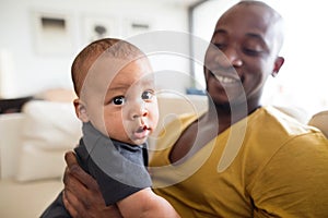 Young afro-american father holding his baby son in the arms