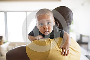 Young afro-american father holding his baby son in the arms