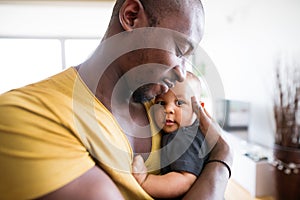 Young afro-american father holding his baby son in the arms