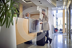 Young  afro-american male paying with card to a friendly female caucasian at reception desk