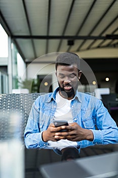 Young Afro American man sitting in cafe and use cell phone