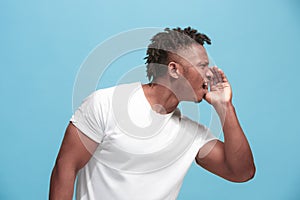 The young afro-american man whispering a secret behind her hand over blue background