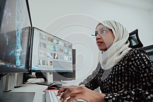 Young Afro-American modern Muslim businesswoman wearing a scarf in a creative bright office workplace with a big screen.