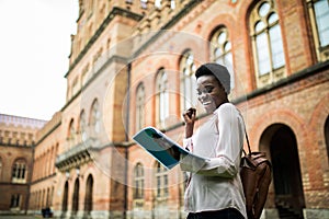 Young afro american student look happy while read notes from textbooks, get points for exams. Young afro student with victory sign