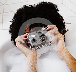 Young afro-american teen girl laying in bath with foam, wearing
