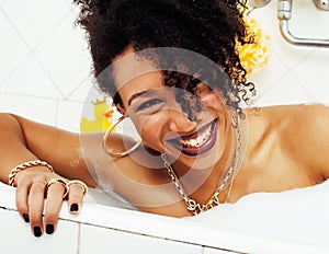 Young afro-american teen girl laying in bath with foam, wearing